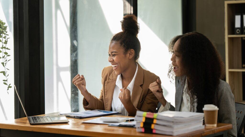 Two black business woman celebrate when business goal success. Achievement and Business Goal Success